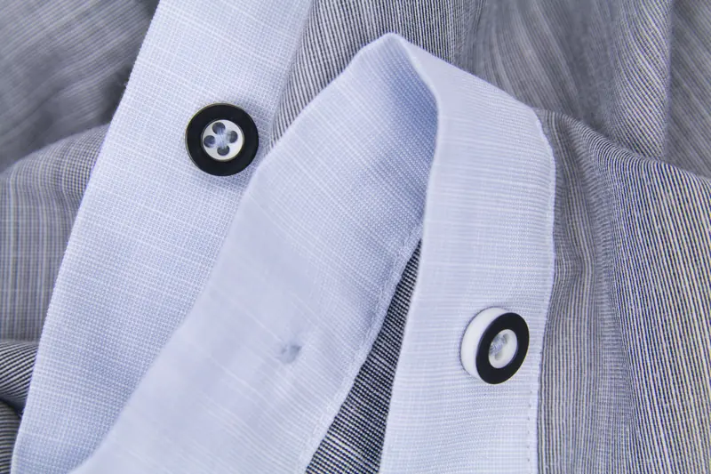 Detailed close-up of black and white buttons on a striped shirt showcasing fabric texture