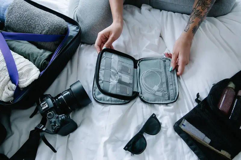 Traveler organizing essentials including a camera and packing cubes on a hotel bed