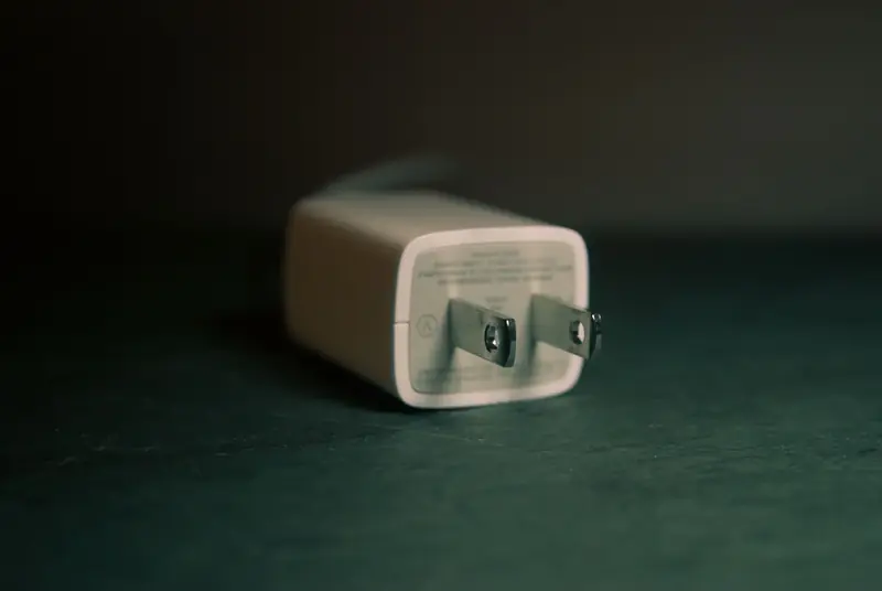 A focused view of a white wall charger plug lying on its side indoors
